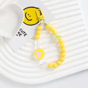 Detailed close-up of yellow beaded phone charm with acrylic heart pendant and flower beads