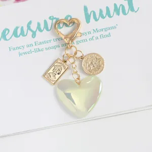 Detail of vintage heart keychain with gold coin pendant and iridescent green heart charm