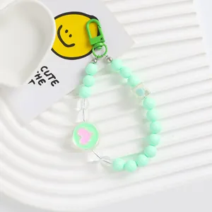 Detail of mint green acrylic beaded phone charm with pink heart pendant and metal clasp