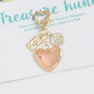 Detail of heart keychain featuring a gold coin pendant and peach resin heart charm