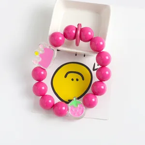 Nahaufnahme des Perlenarmbandes mit Anhängern in Form von Erdbeeren und Kronen aus Acryl