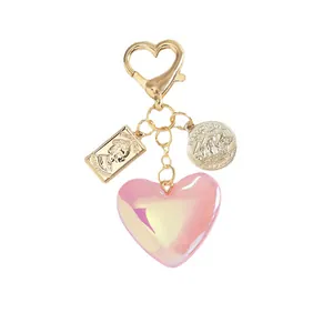 Pink resin heart keychain with vintage gold queen coin and sailboat charms on white base