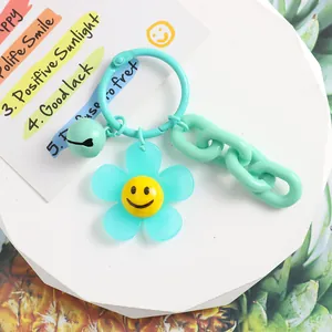 Gros plan du porte-clés fleur bleue avec visage souriant, clochette et chaîne acrylique