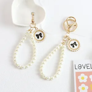 Detail of pearl keychain with gold lobster clasp and black bow pendant with number five