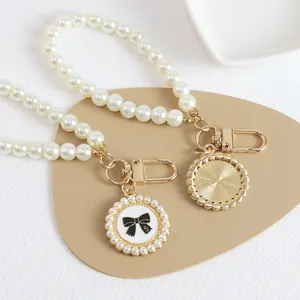 Detail of beaded pearl keychain with golden number 5 bow charm and metal lobster clasp