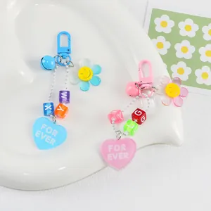 Détail de porte-clés tournesol en acrylique avec smiley, perles alphabet et cœur rose
