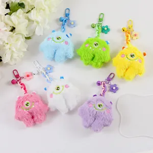 Flat lay of colorful plush monster keychains with metal clips, bells and floral charms