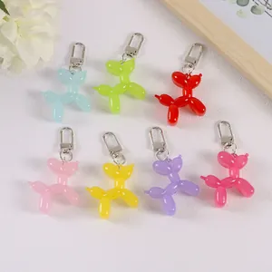 Flat lay of colorful resin balloon dog keychains in seven bright colors with silver clasps