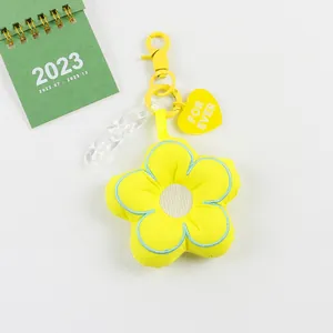 Detail van gele pluche bloem sleutelhanger met hartvormige hanger en ketting