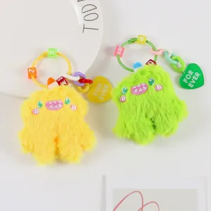 Close-up of cute plush monster charms in yellow and green with colorful beaded straps