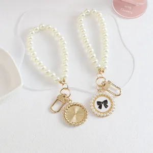 Detailed view of pearl beaded strap with golden lobster clasp and bow pendant charms