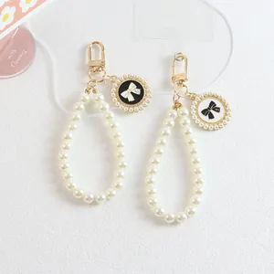 Close-up of pearl bead charms with gold clasp and bow pendant featuring the number five
