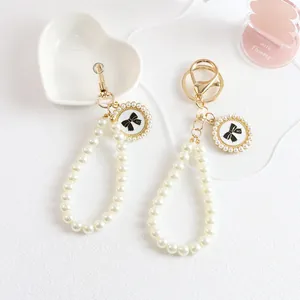 Close-up of pearl bead keychain with golden number 5 bow charm and metal clasp detail