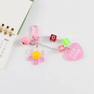 Détail de porte-clés marguerite rose en acrylique avec perles lettres et pendentif cœur