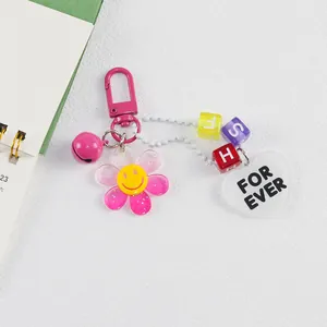 Détail du pendentif fleur en acrylique avec perles de lettres et étiquette cœur