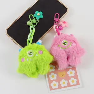 Close-up of plush monster keychains in green and pink with cute embroidered eyes