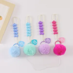 Detail of colorful plush pompom keychains with pearl chains and heart-shaped charms