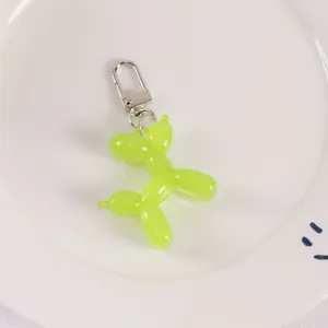 Detailed view of neon green jelly balloon dog keychain with silver lobster clasp on white tray
