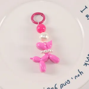 Detail of pink balloon dog keychain with elegant white pearls and a metallic ring hook