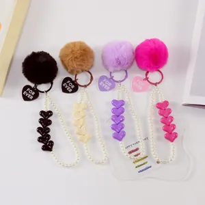 Detail of four colorful plush heart keychains with pearls and engraved metal pendants
