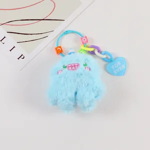 Blue plush monster keychain with embroidered face and heart pendant detail