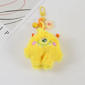 Detail of yellow plush monster keychain with embroidery, lobster clasp and floral charm