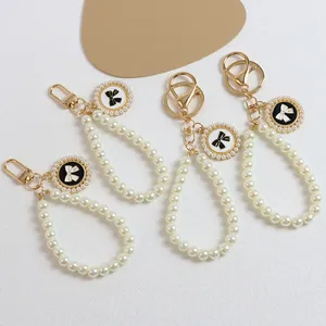 Elegant pearl bow keychain charm set with metallic gold rings and number five pendant