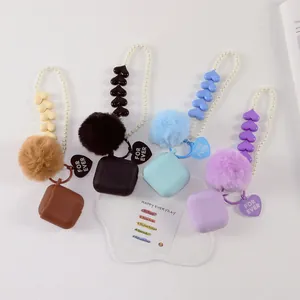 Close-up of silicone earphone cases with plush fur balls and pearl heart-shaped charms
