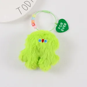 Detail of neon green plush monster keychain with smiling beads and For Ever heart tag