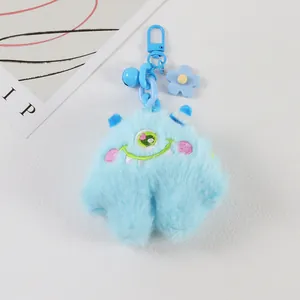 Detail of blue plush monster keychain with embroidery, bell and flower accessory