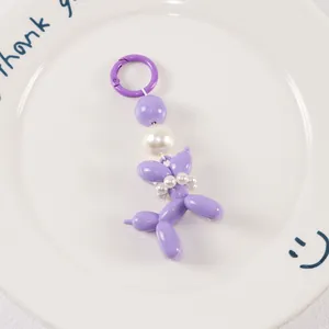 Detailed macro view of purple balloon dog keychain with elegant white pearl collar