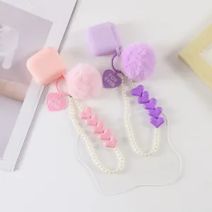 Detail of pink and purple earphone cases with plush pompom and pearl heart charms