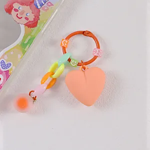 Dettaglio di un portachiavi a cuore colorato con perline smiley e cuore in acrilico arancio