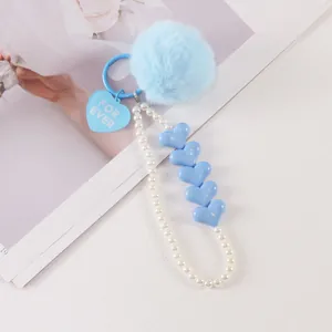 Detail of blue plush pompom keychain with pearl chain and heart-shaped for ever tag