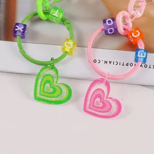 Dettaglio di portachiavi a cuore Y2K rosa e verdi con perline colorate e finitura glitterata