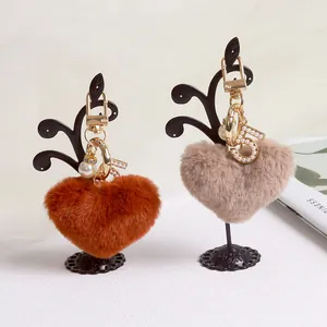 Plush heart keychain set in orange and beige with pearl number 5 charm on jewelry stand