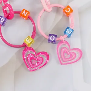 Dettaglio portachiavi a cuore glitter rosa con perline colorate a forma di lettere