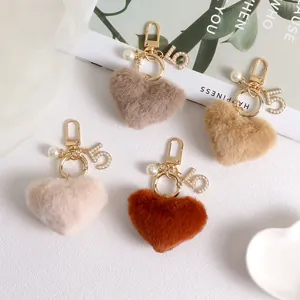 Detail of plush heart keychains in earth tones featuring pearl charms and gold hardware