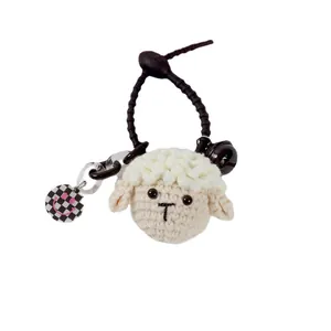 Handmade crochet sheep keychain with black bell and checkered smile pendant on white background