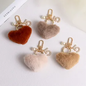 Macro view of plush heart keychains with pearls and gold number five charms on white background