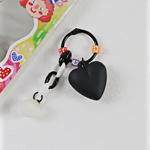 Dettaglio del ciondolo a cuore nero opaco con perline smiley colorate e catena in acrilico