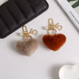 Close-up of heart-shaped plush keychains with pearl charms and crystal number five charms