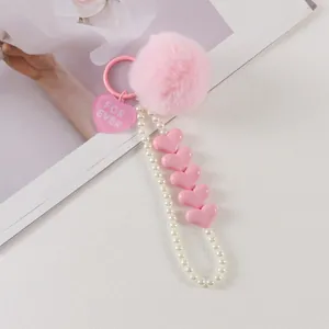 Pink faux fur pompom keychain with white pearl chain and heart charms detail