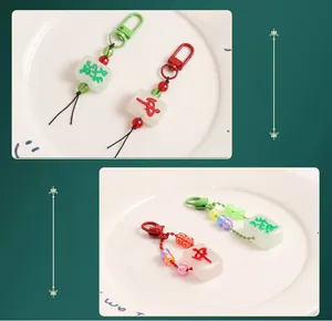 Detailed macro view of Mahjong keychains with red and green beads and metal lobster clasps