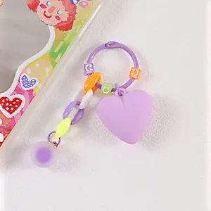 Dettaglio portachiavi a cuore con catene colorate e perline a forma di smile su base bianca