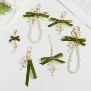 Detalle de colgantes con lazos de terciopelo verde oliva, perlas y lirios de los valles