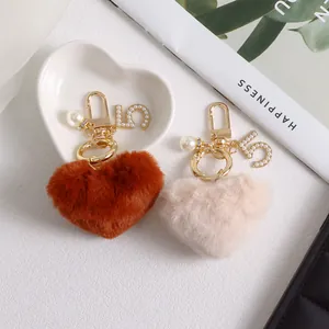 Detail of plush heart keychains with pearls and gold number 5 charms on a white plate