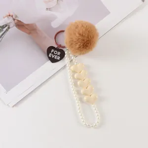 Detail of faux fur pompom and pearl beaded lanyard with black heart forever tag