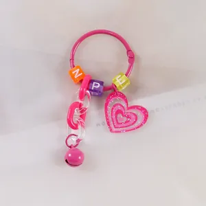 Dettaglio portachiavi rosa a cuore con perline alfabetiche, catena e campanellino