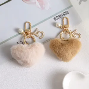 Close-up of plush heart keychains with pearls and gold number 5 charm on a magazine